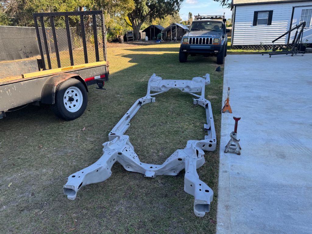 1984 Buick Grand National frame after blasting — completely clean white/gray bare steel chassis, all rust removed, ready for restoration