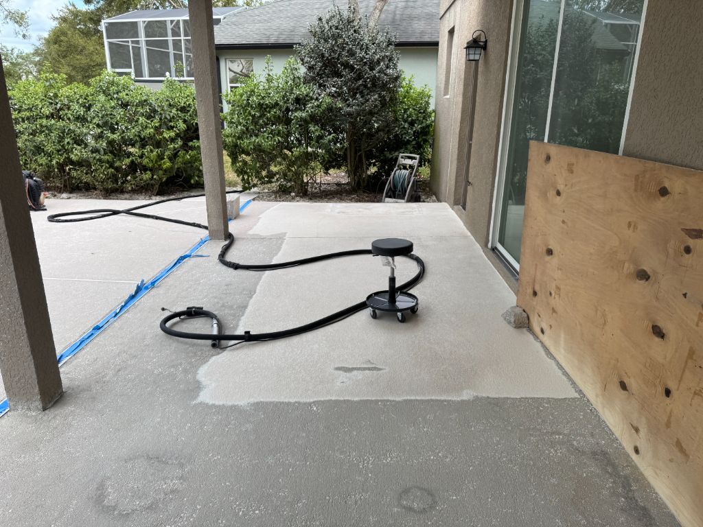 Black Ox crew sandblasting epoxy paint off a pool deck — hoses laid out, work in progress on covered patio