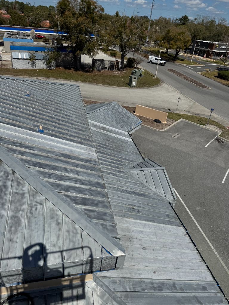 Aerial view of vet clinic roof after — all 7,000 sq ft of blue paint removed, bare metal exposed